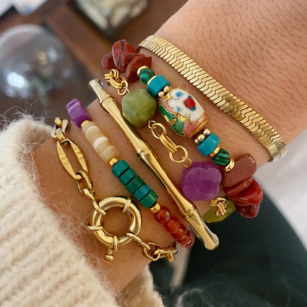 Een pols met kleurrijke armbanden in bohemian style met bruine, paarse, groene en turkooise edelstenen.