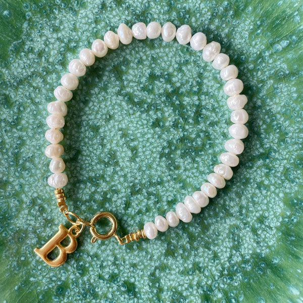 Armband geregen van fijne onregelmatige zoetwaterparels met een gouden initiaal.