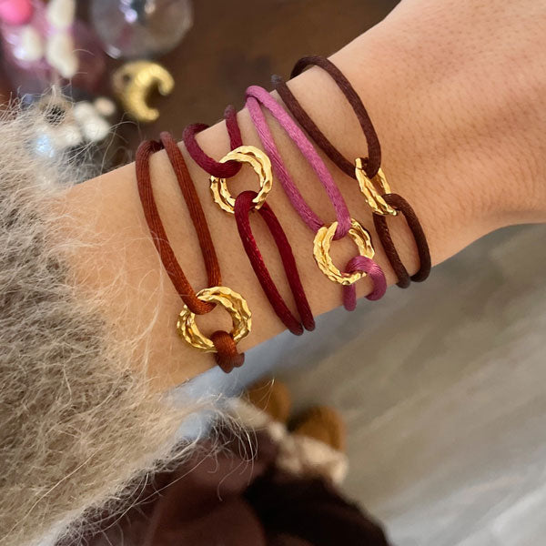 Armband Cartierknoop Infinity goud met rood, bruin of vintage roze satijnkoord. in het midden een gouden infinity bedel