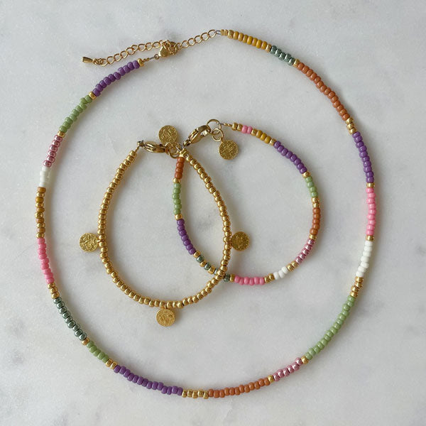 DIY sieraden pakket armband en ketting maken met gouden muntjes en pastel kleurige kralen.