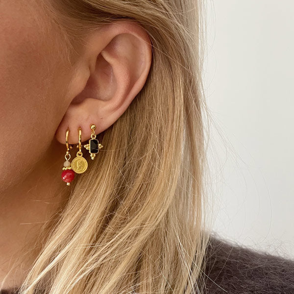 set van drie gouden oorbellen waaronder een gouden muntje, een rode edelsteen en een zwarte onyx.