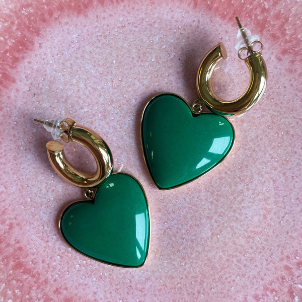 oorbellen met een groot groen hart aan gouden oorringen.