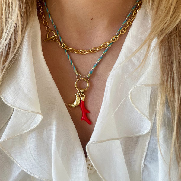 Ketting gemaakt van geweven twisted koord en een gouden ringsluiting. Aan de sluiting hangt een rood koraaltakje en een gouden croissantje.